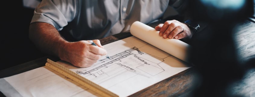 An architect working on a draft with a pencil and ruler